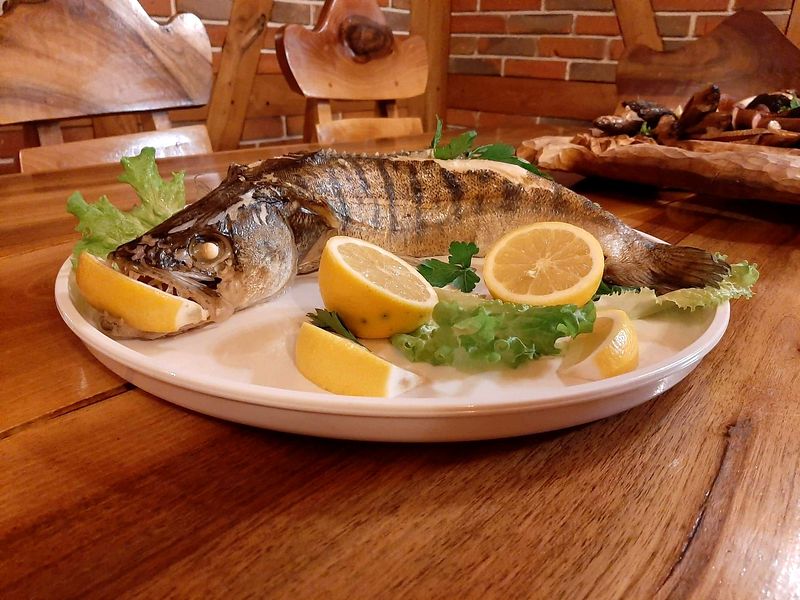 Pieczona ryba z cytryną i sałatą na białym talerzu