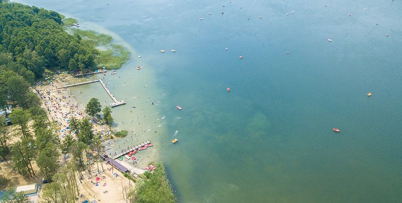 Plaża w Boszkowie-Letnisku z lotu ptaka: pomosty, kąpiący się i turkusowa płycizna Jeziora Dominickiego